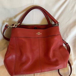 Small, red coach handbag with detachable shoulder strap.